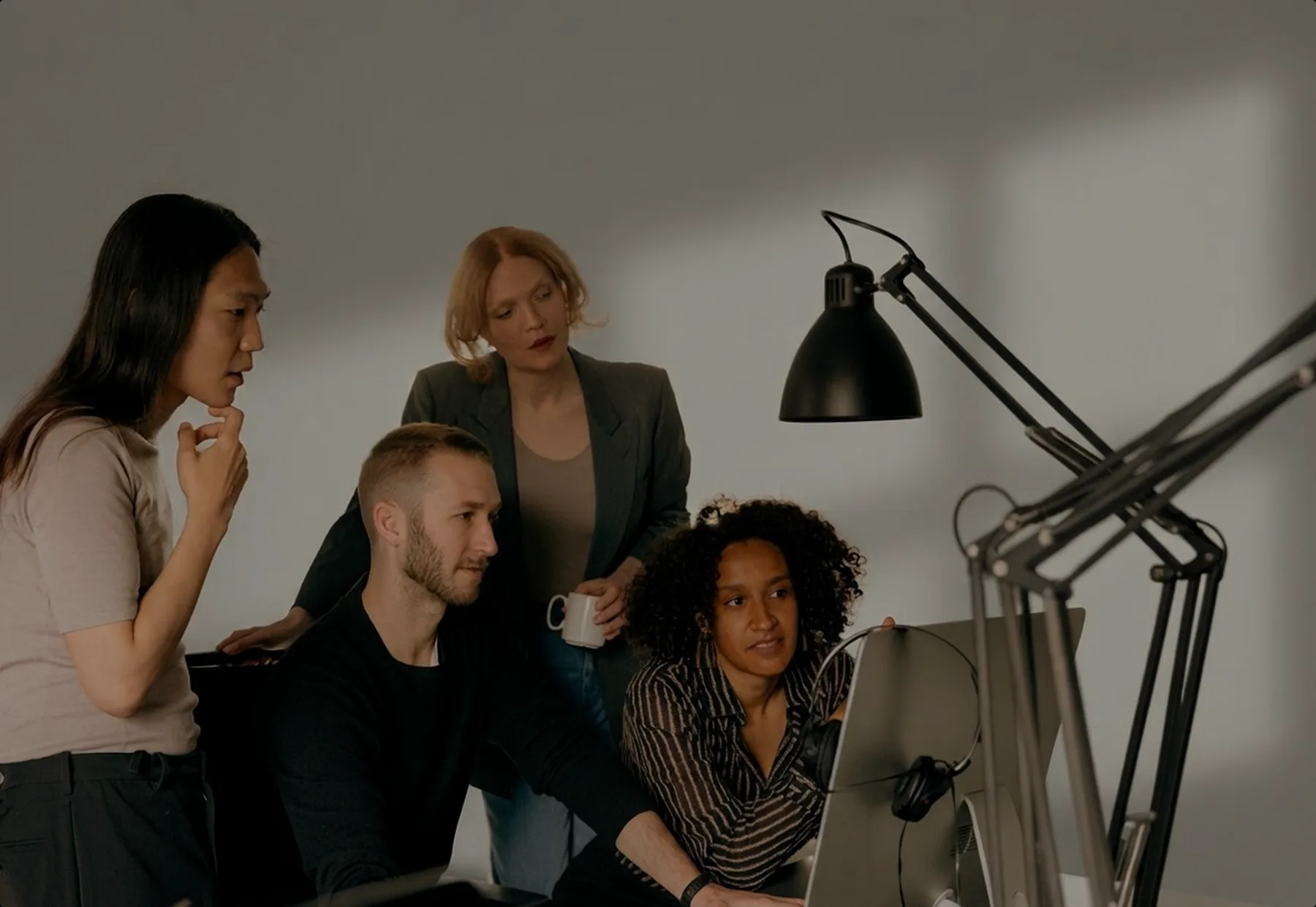Four teammates gathered around one monitor in a studio office
